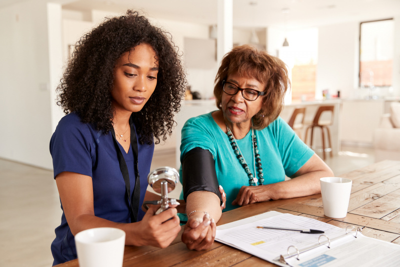   vanema mustanahalise naise kodus mõõdab noor mustanahaline tervishoiutöötaja vererõhku