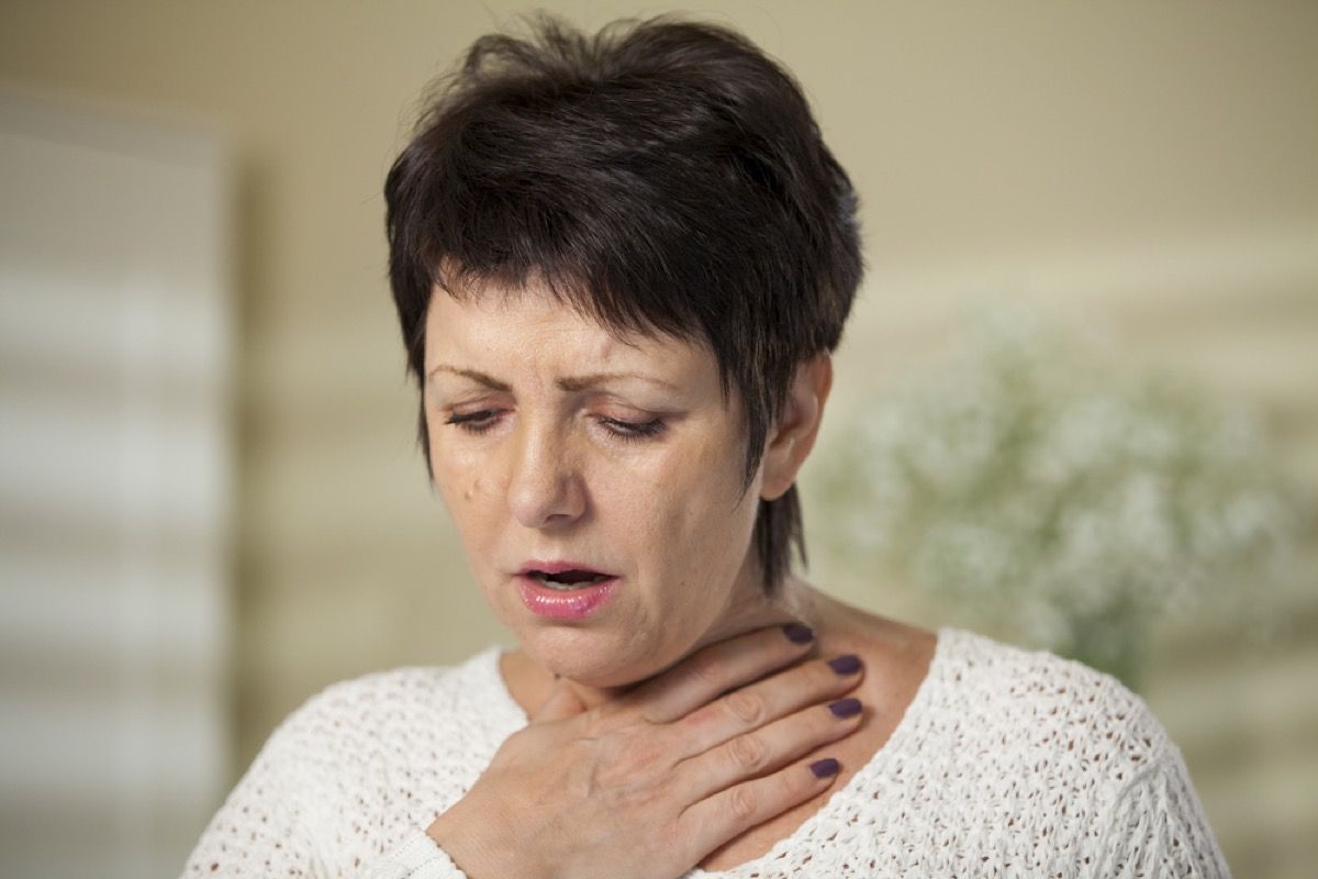 eldre kvinne klemmer seg i halsen, tegn på at forkjølelsen din er alvorlig