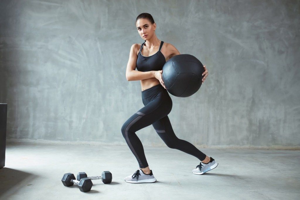 אישה באימון ללבוש ספורט מסוגנן עם כדור מד - תמונה