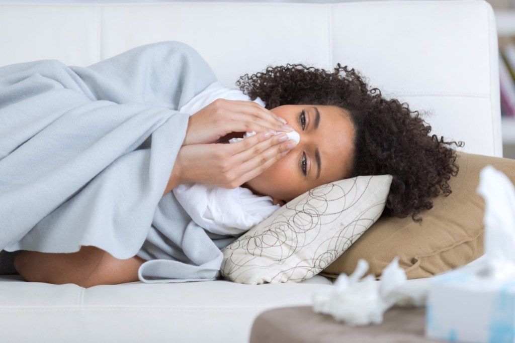 Mulher fungando doente com gripe {Surprising Flu Symptoms}