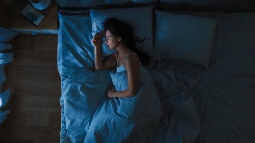 אישה ישנה בשמחה במיטה בלילה