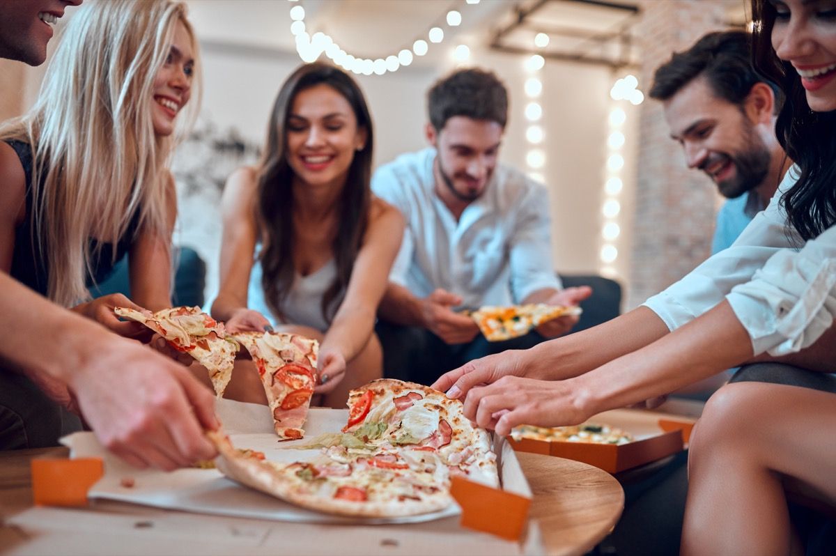 חברים שמבלים ואוכלים פיצה עם הרבה תוספות ביחד