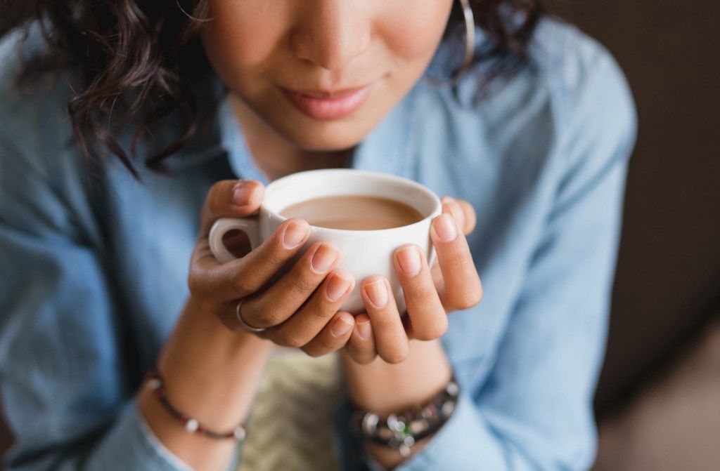 Femeie care încearcă să miroasă o ceașcă de cafea