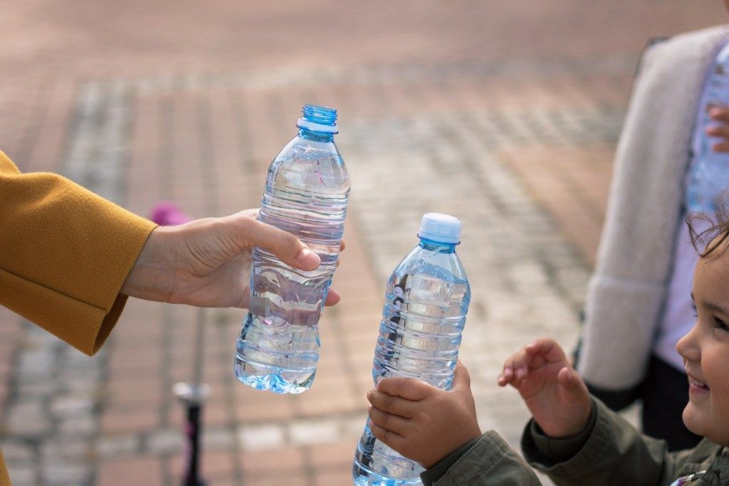 Od blizu mama in hči nazdravlja s steklenicami za vodo.