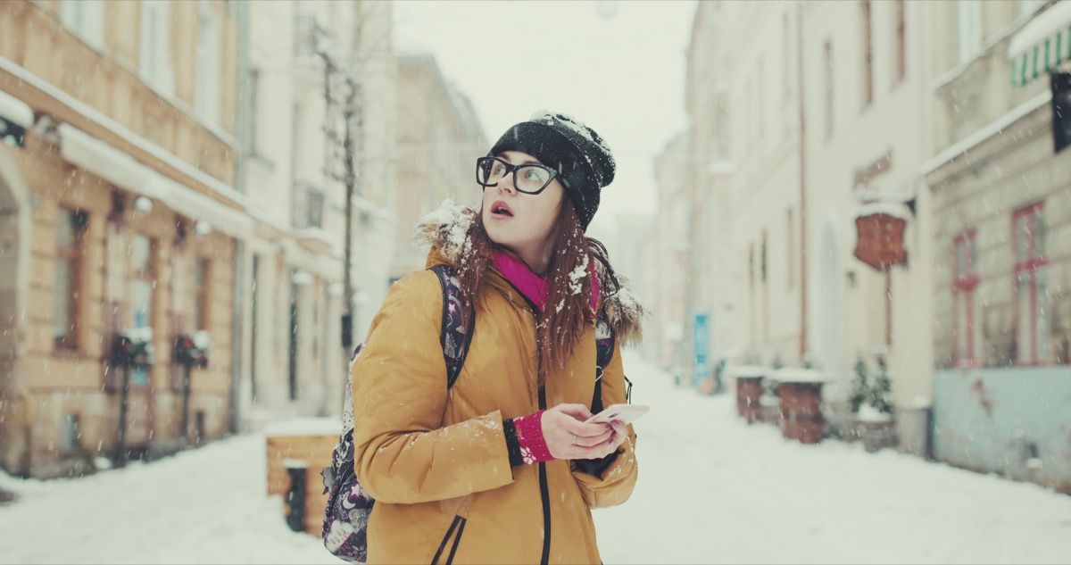 Mujer confundida perdida caminando por la nieve con el teléfono
