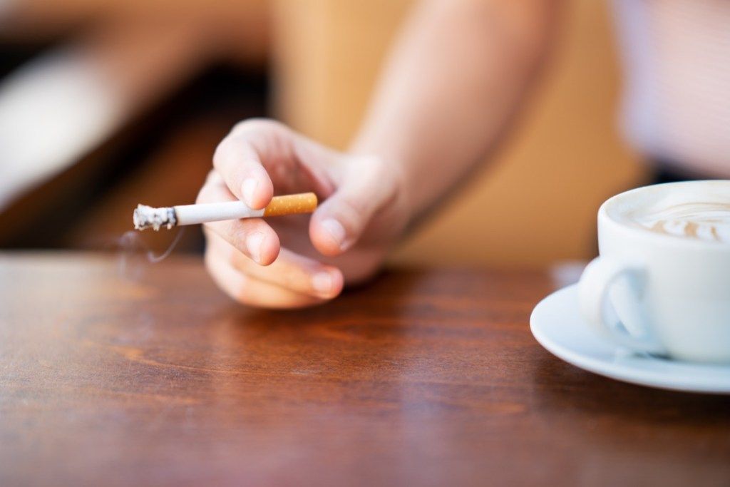 Mujer fumando mientras bebe café en un café