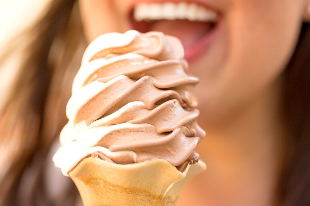 Mujer comiendo helado de chocolate y vainilla en un cono