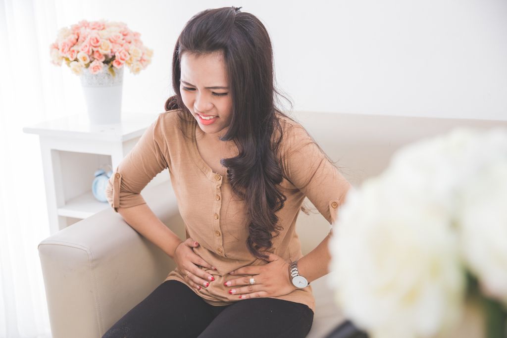 mujer asiática que experimenta dolor de estómago