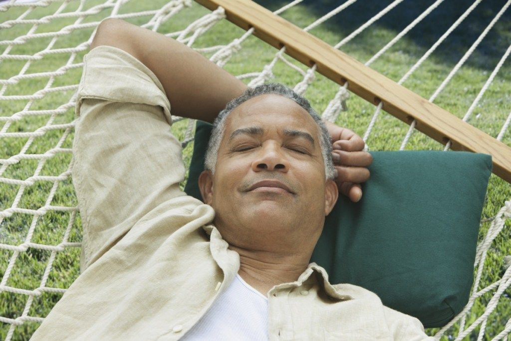 Eldre svart mann som sover på en hengekøye