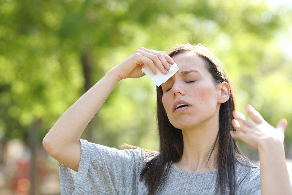 Ženska, ki suši znoj z robčkom v toplem poletnem dnevu