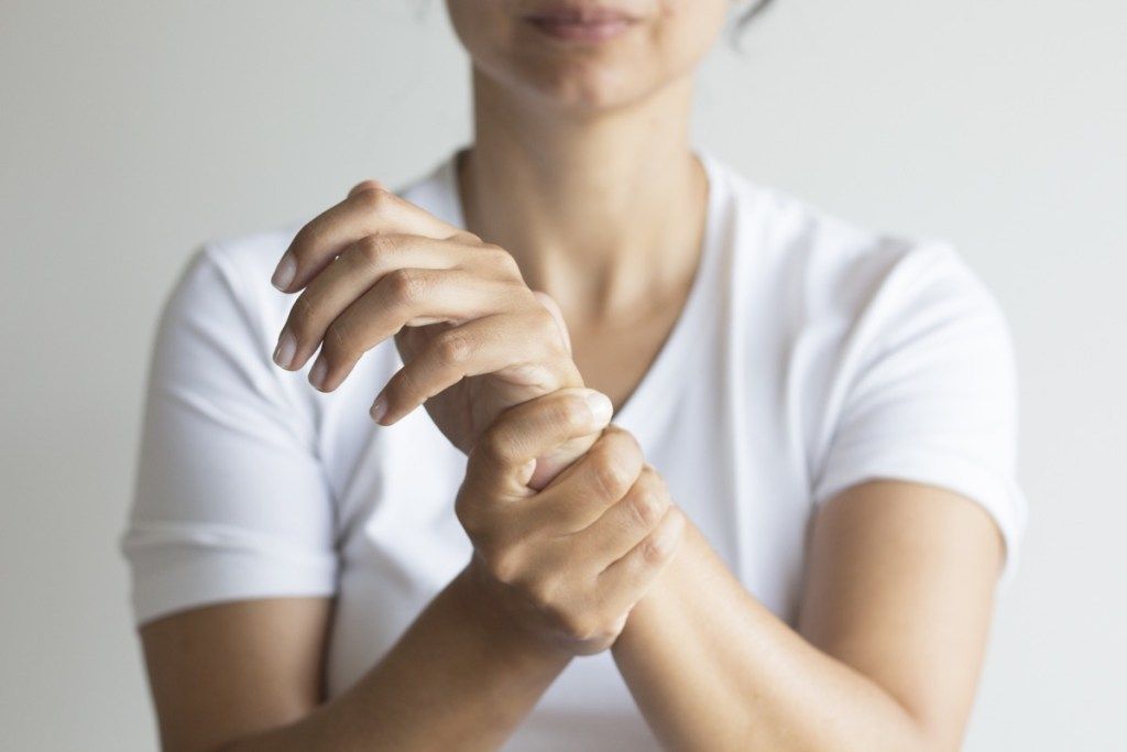 ผู้หญิงกำลังจับข้อมือจากความเจ็บปวด