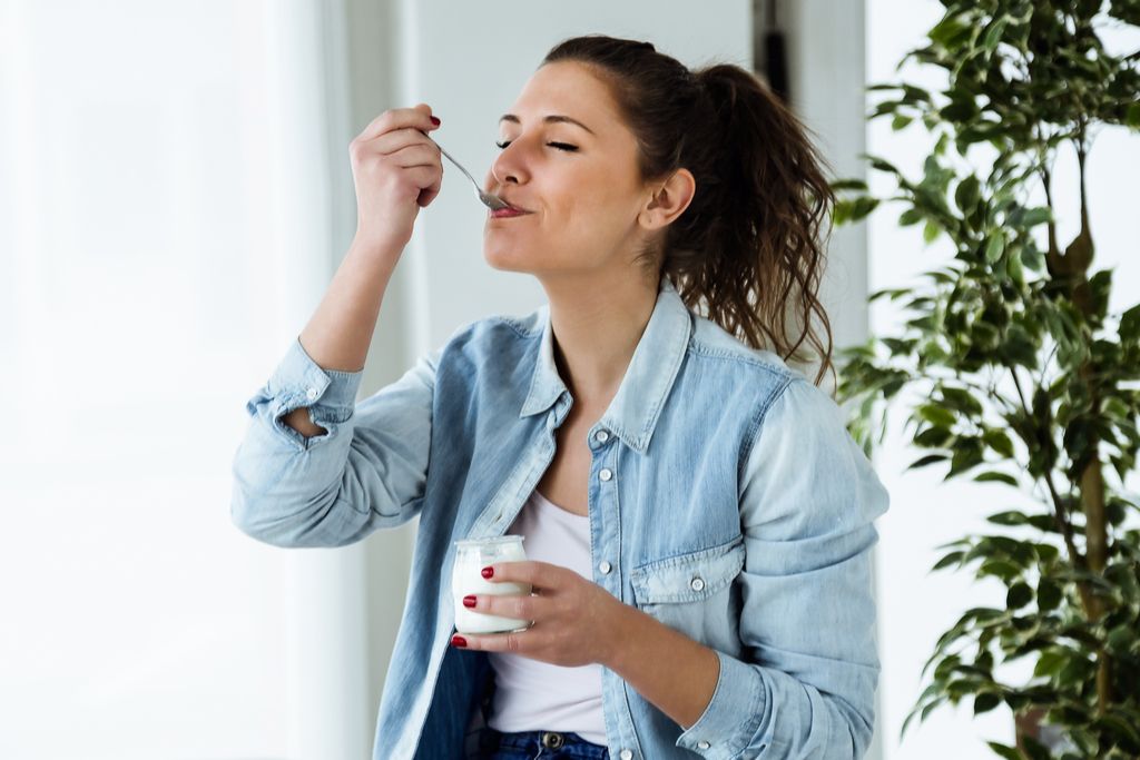 Mulher comendo iogurte antienvelhecimento
