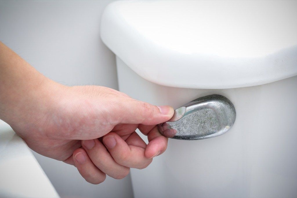 Balta ranka praplauna tualetą vonioje