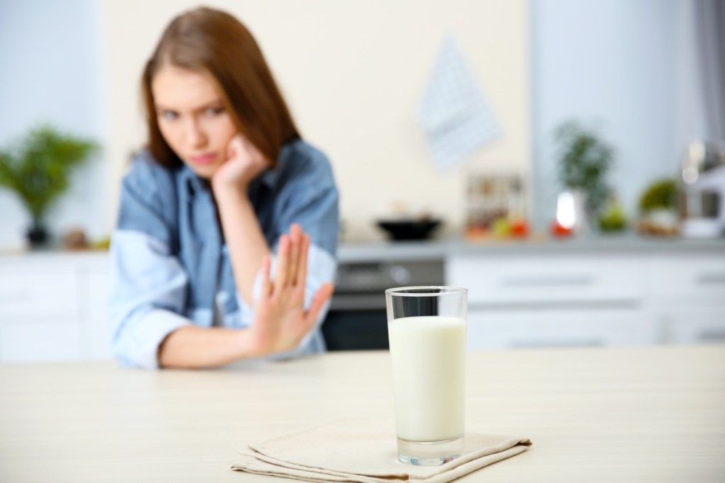 jauna balta moteris atsisako stiklinės pieno