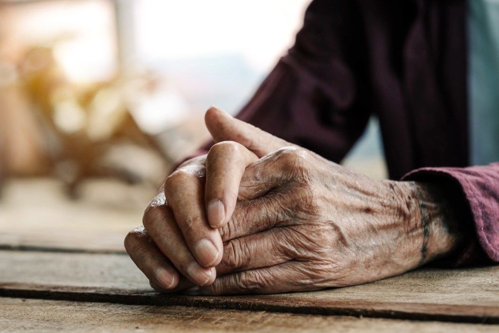 Roke starca na leseni mizi. Vintažni ton - slika