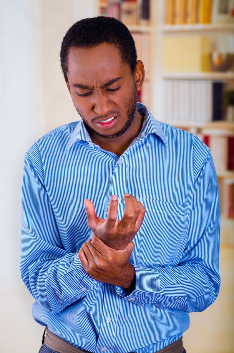 Черен мъж, който държи китката си от болка поради синдром на карпалния тунел