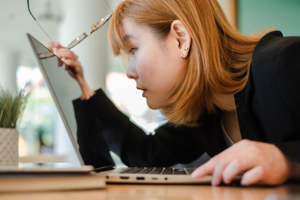 אישה אסייתית צעירה מסתכלת על מחשב נייד