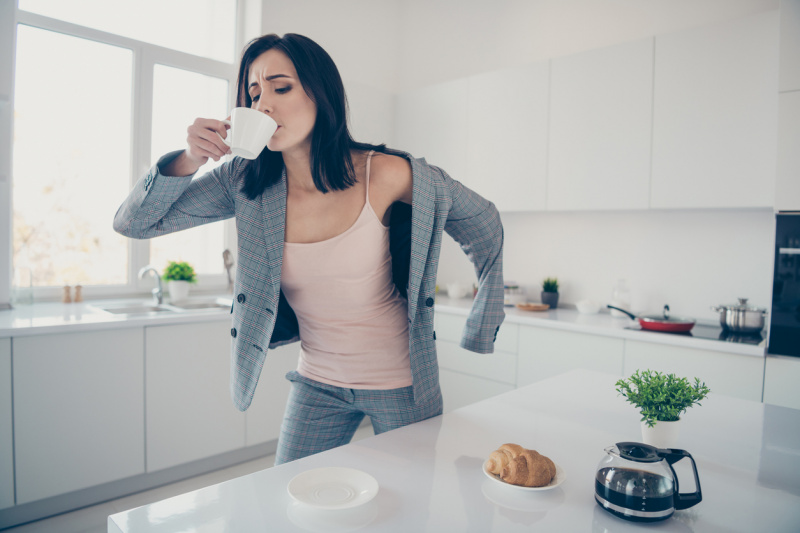   Žena pije kávu a ráno si oblieka sveter.