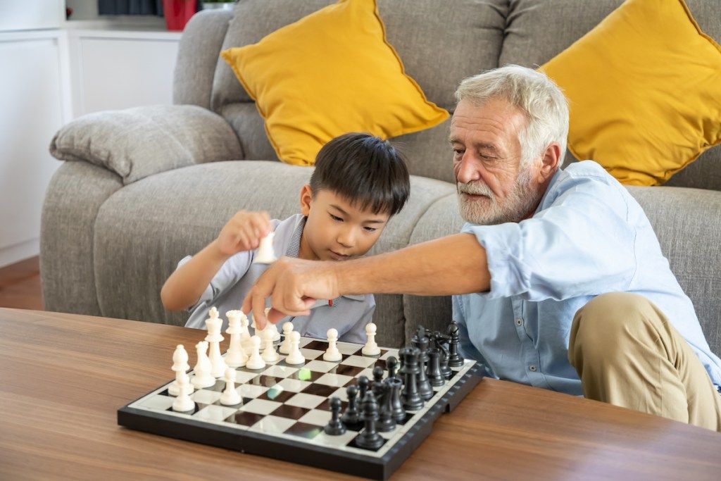 Mann som spiller sjakk med barnebarnet sitt
