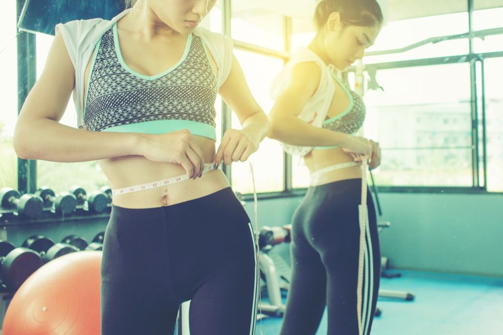 жена във фитнес зала, измерваща загуба на тегло и талия остават остри