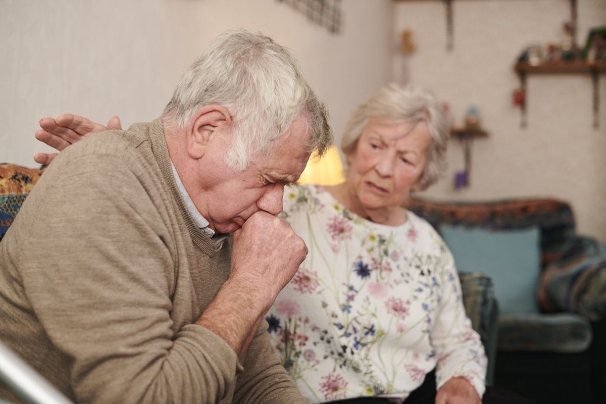 starejši moški z ženo doma, ki močno kašlja, kaže, da je vaš prehlad resnejši