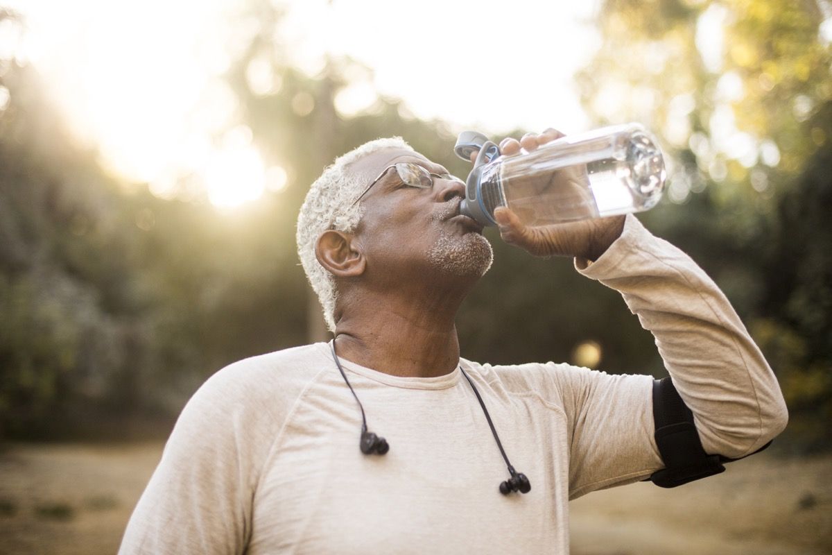 Seorang lelaki Afrika Amerika yang senior menikmati air yang menyegarkan setelah bersenam