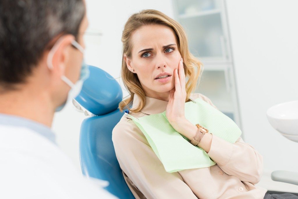 امرأة عند طبيب الأسنان تعاني من ألم في فكها