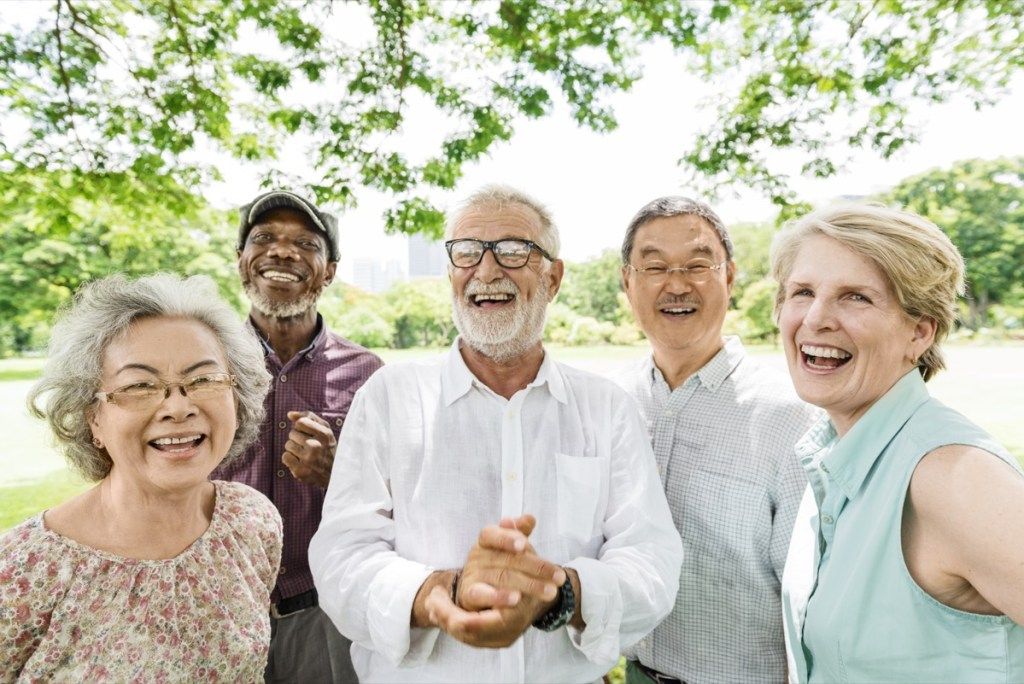 एक पार्क में वृद्ध लोगों का बहुस्तरीय मुस्कुराता हुआ समूह