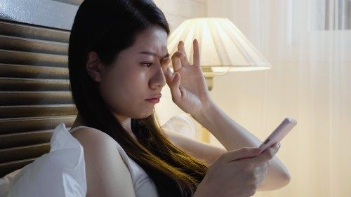 Vrouw wrijft haar ogen van pijn omdat ze haar mobiele telefoon gebruikt