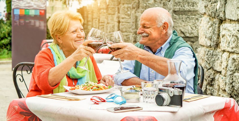 زوجان مسنان يشربان النبيذ ويأكلان في إيطاليا