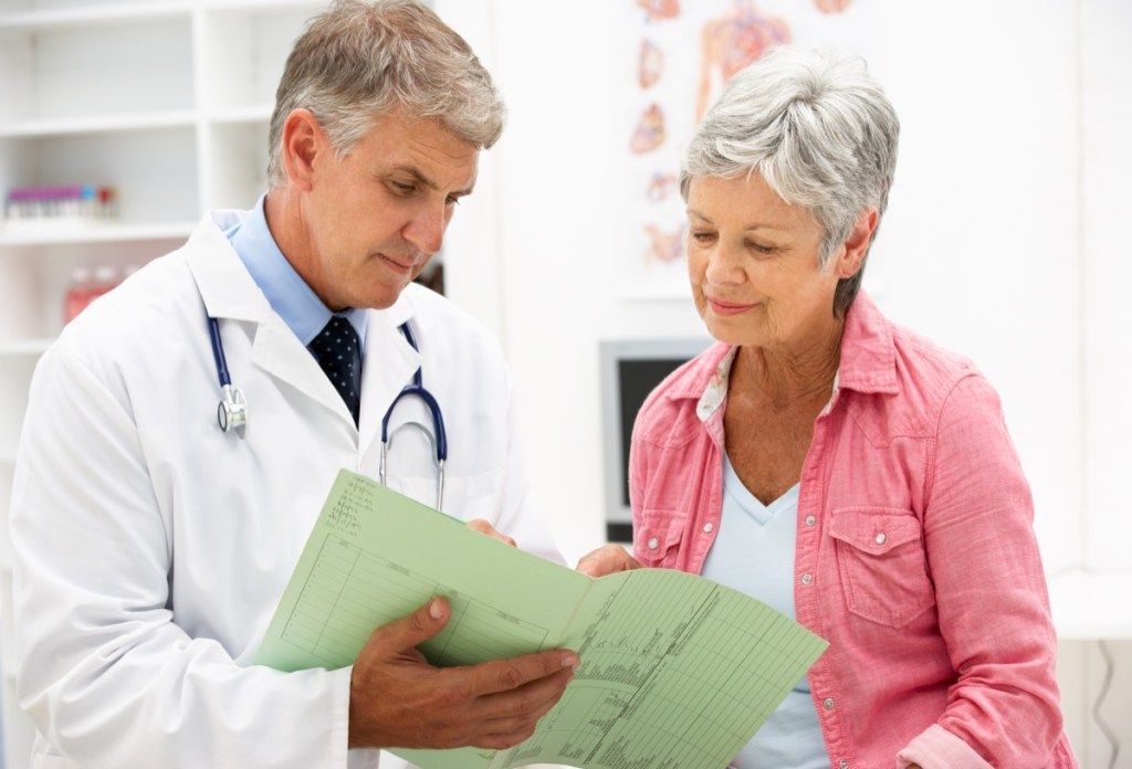 Senior woman avec de courts cheveux gris parlant à un médecin senior de sexe masculin blanc, nid vide