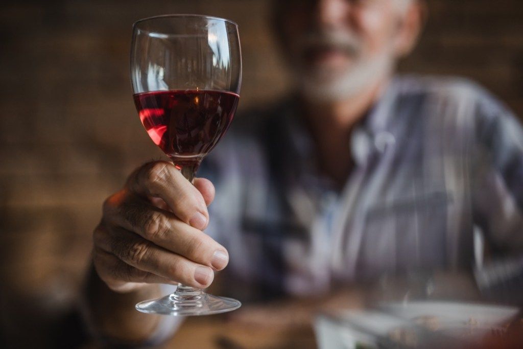 lelaki yang lebih tua memegang segelas anggur merah