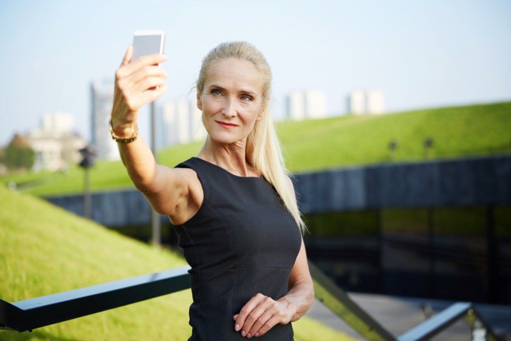 Pārliecināta vecāka sieviete, kas uzņem selfiju
