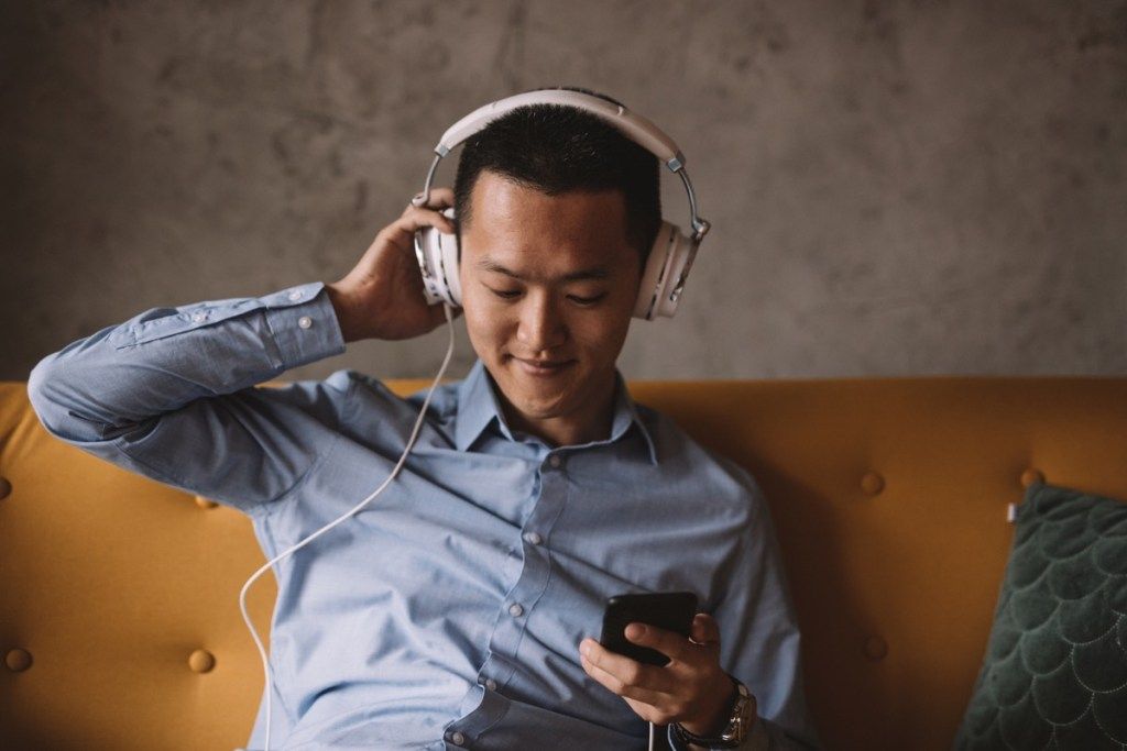 Pemuda Asia mendengarkan musik dan bersantai di kantornya