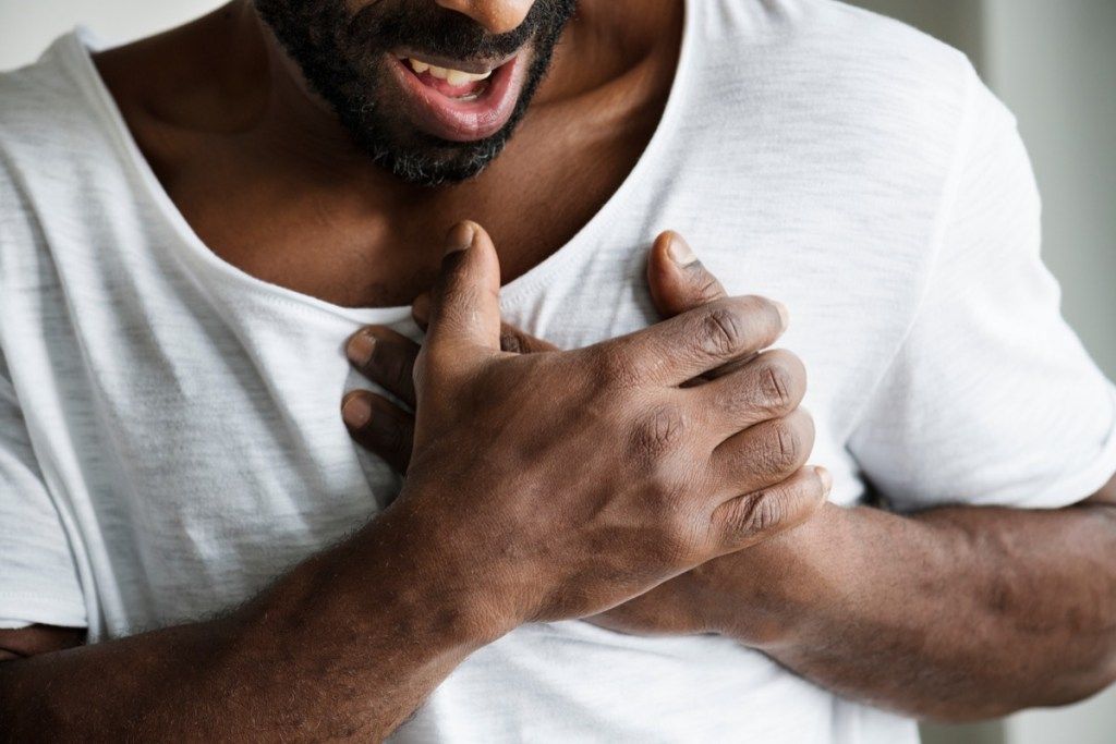 moški, ki se stiska za prsi, ima težave s srcem
