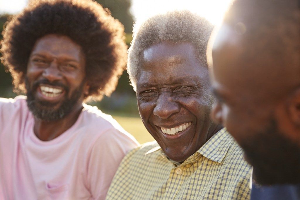 Vanem mustanahaline mees naeris koos kahe täiskasvanud pojaga