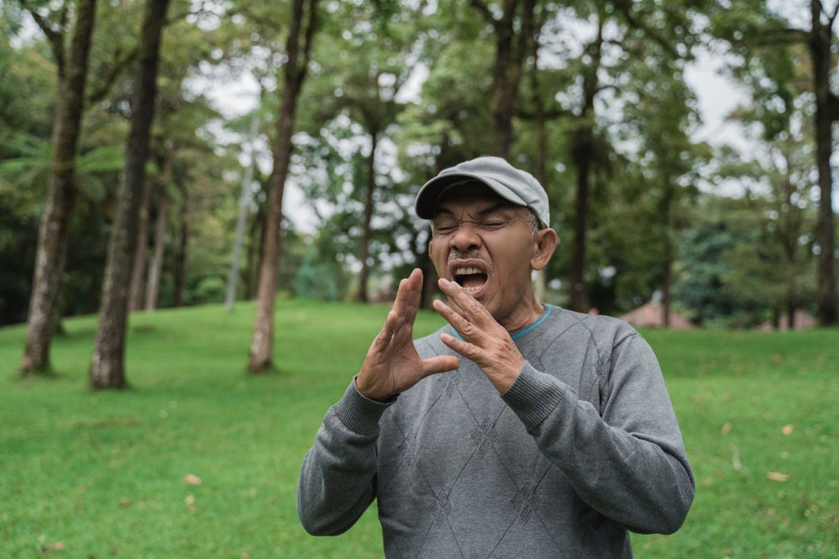 גבר דרום אסייתי מתעטש בפארק מבלי לכסות פה, נימוסים מעל גיל 40
