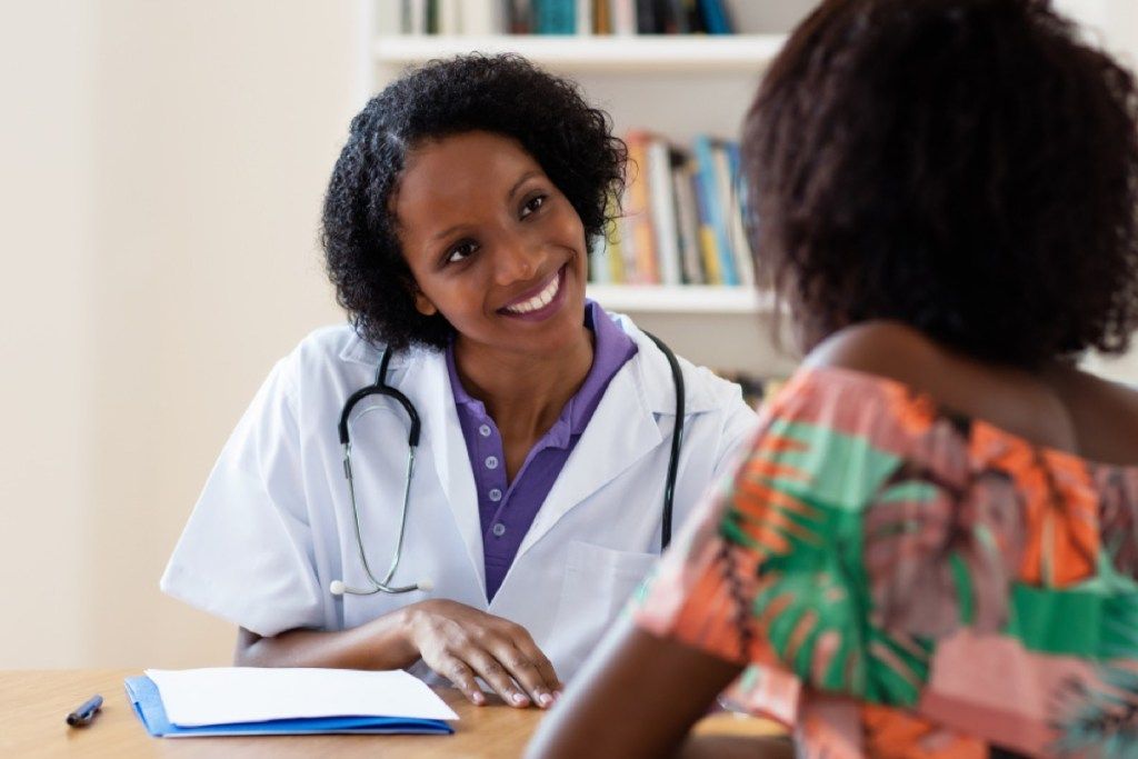 ung sort læge taler med kvindelig patient, hudkræft fakta