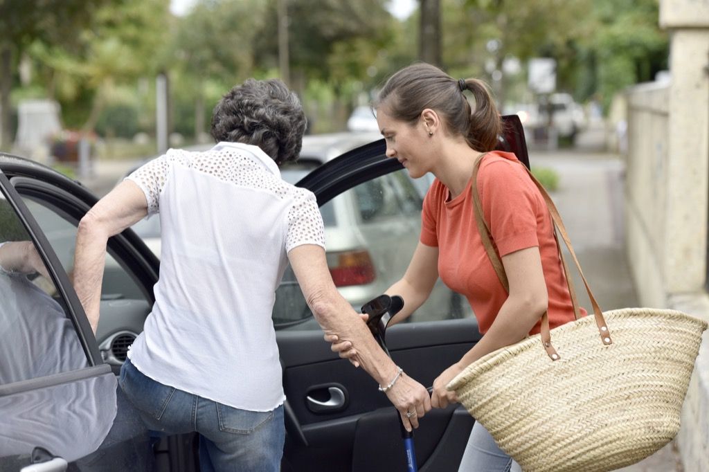 Žena pomáhá starším občanům nastoupit do auta