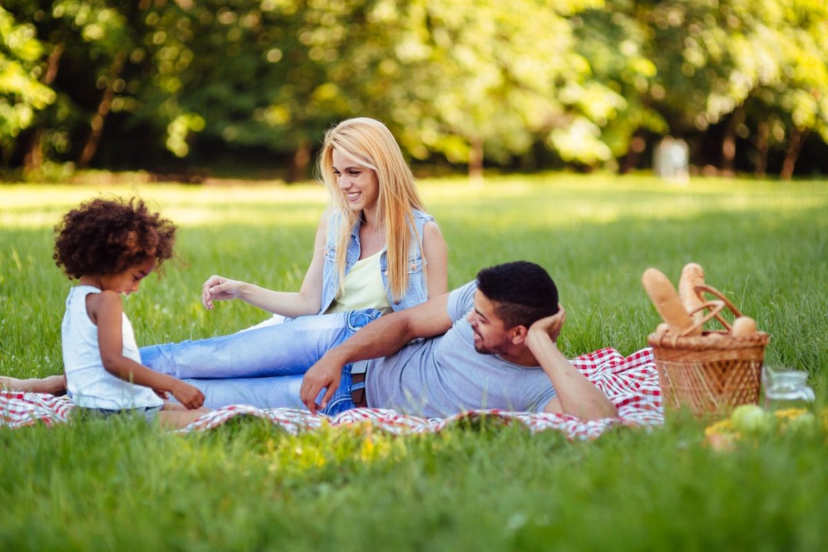 外でピクニックをしている若い娘と白人女性とラテン系男性