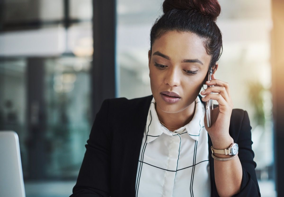 Imagine a unei tinere femei de afaceri folosind un telefon mobil într-un birou modern