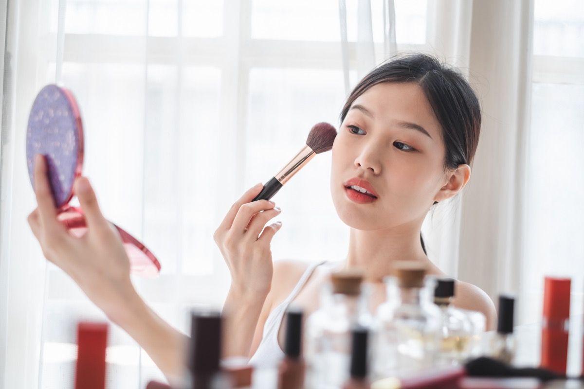 Mladá krásna žena použitie kozmetiky make-up na tvári, starostlivosť o zdravie pokožky a make-up koncept