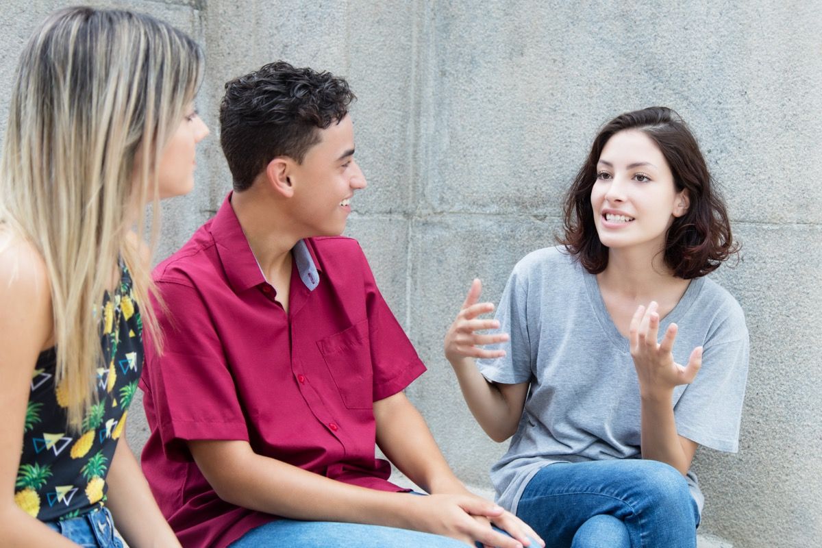 Trys jauni suaugusieji vasarą diskutuoja lauke