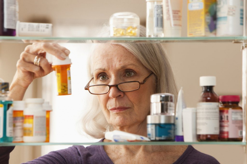   Възрастна жена гледа бутилки с рецепта