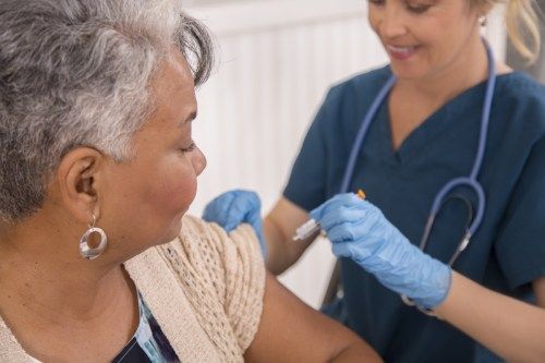 Medicinska sestra daje cepivo proti gripi starejšemu odraslemu bolniku v lokalni lekarni, kliniki ali zdravniku