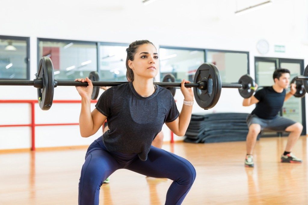Kvinde laver en barbell squat i en træningsklasse