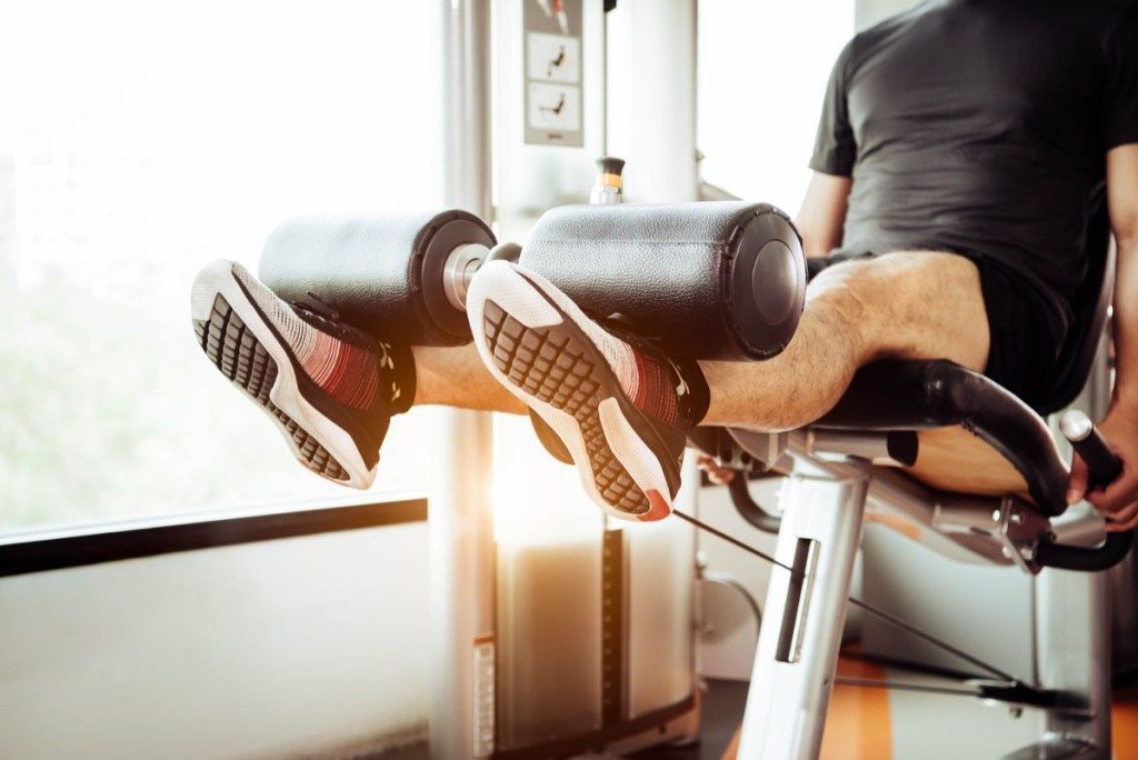 Pria yang menggunakan mesin ekstensi kaki di gym