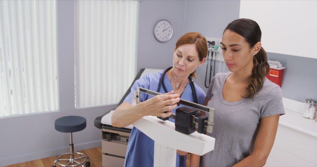 Mujer pesando en una balanza en el médico