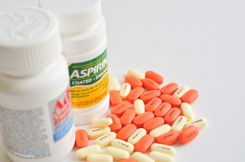   Píldoras de aspirina y advil sobre fondo blanco.