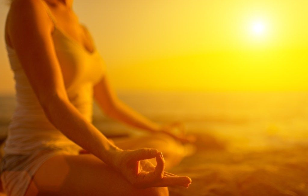 жена, медитираща при залез слънце